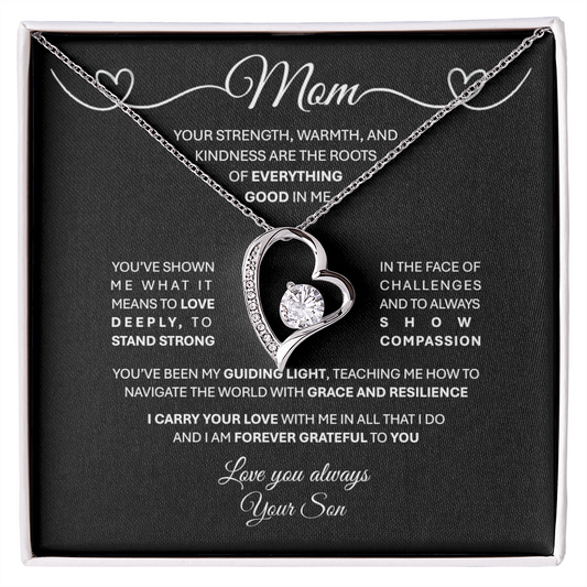 A Forever Love Necklace presented in a black box with a message to the mom, highlighting the meaning of the necklace. The necklace features a polished heart pendant with a cubic zirconia at its center, surrounded by smaller crystals, and an adjustable chain.